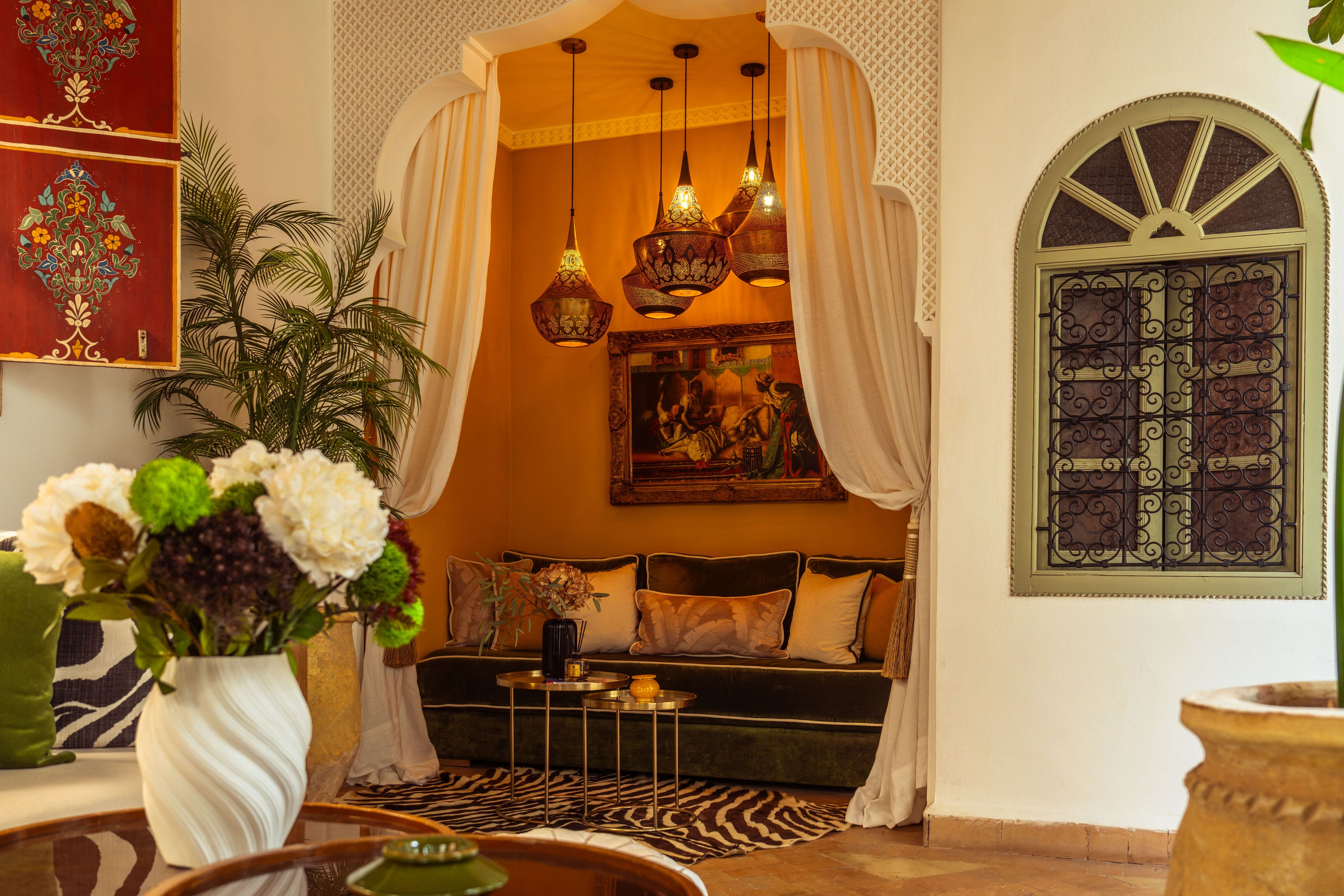 A cozy lounge area with a sofa, decorative lamps, a vase of flowers, and a patterned rug.