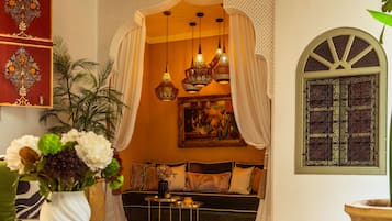 A cozy lounge area with a sofa, decorative lamps, a vase of flowers, and a patterned rug.