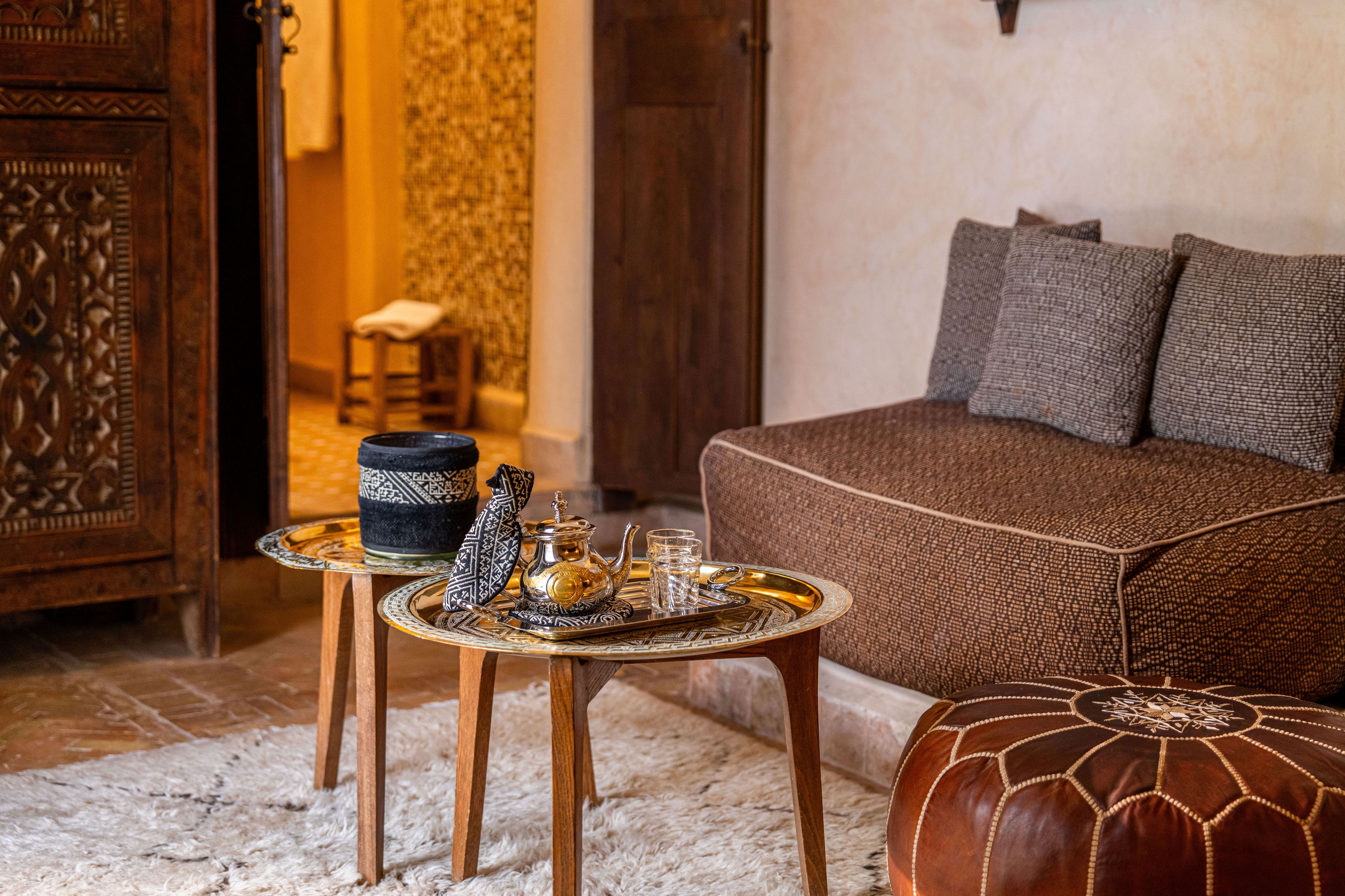 A cozy room with a sofa, a decorative tray with a teapot and cups, and a patterned ottoman.