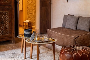 Una habitación acogedora con un sofá, una bandeja decorativa con tetera y tazas, y un reposapiés estampado.