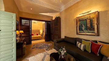 A hotel room with a bed, a sitting area with a sofa, a chandelier, and a painting on the wall.