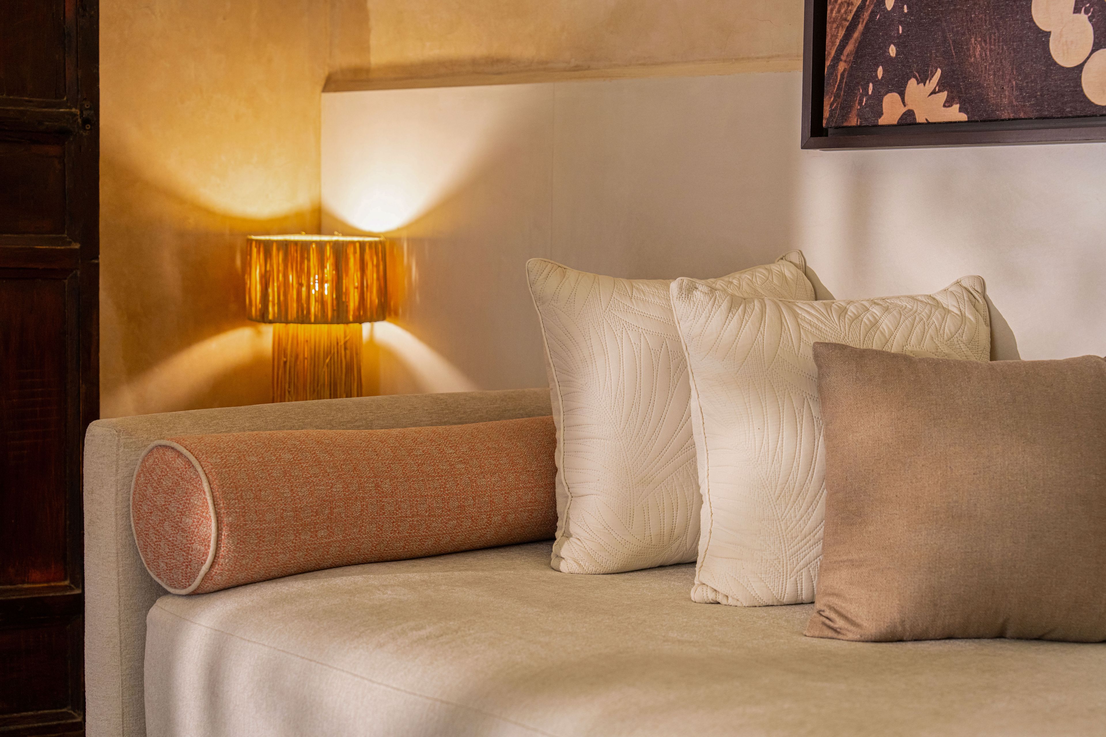 A bed with a headboard, a lamp, and multiple pillows.