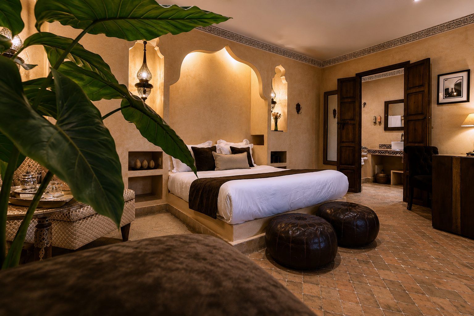 A hotel room with a large bed, a sitting area with a table, and a bathroom visible through an open door.