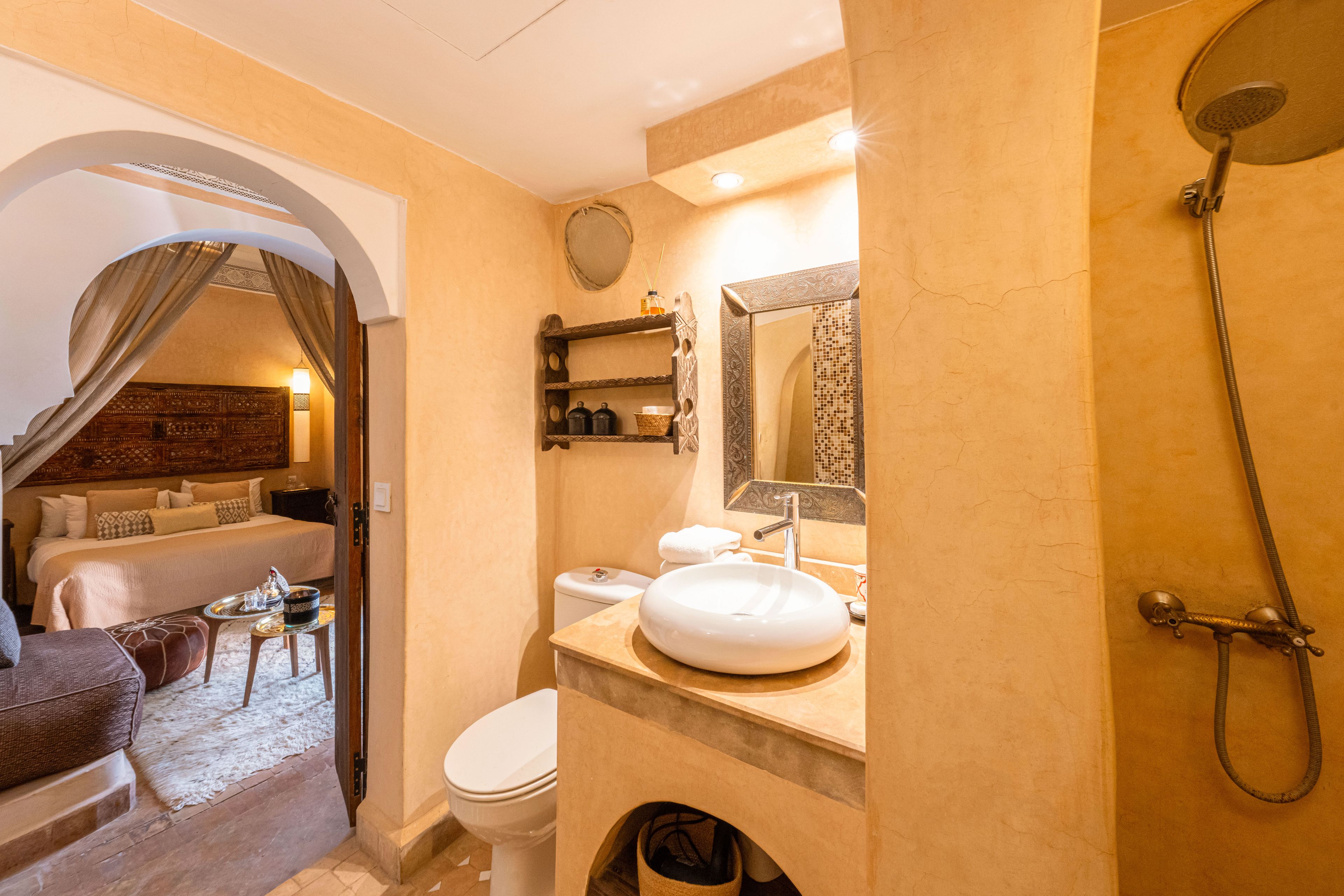 A bathroom with a bathtub, a sink, and a toilet. There is a mirror above the sink and a showerhead on the wall.