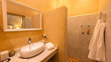 A bathroom with a large mirror, a sink, a towel rack, and a shower area.