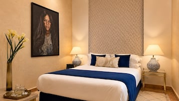 Una habitación de hotel con una cama grande, dos lámparas de noche, un florero con flores y un cuadro en la pared.