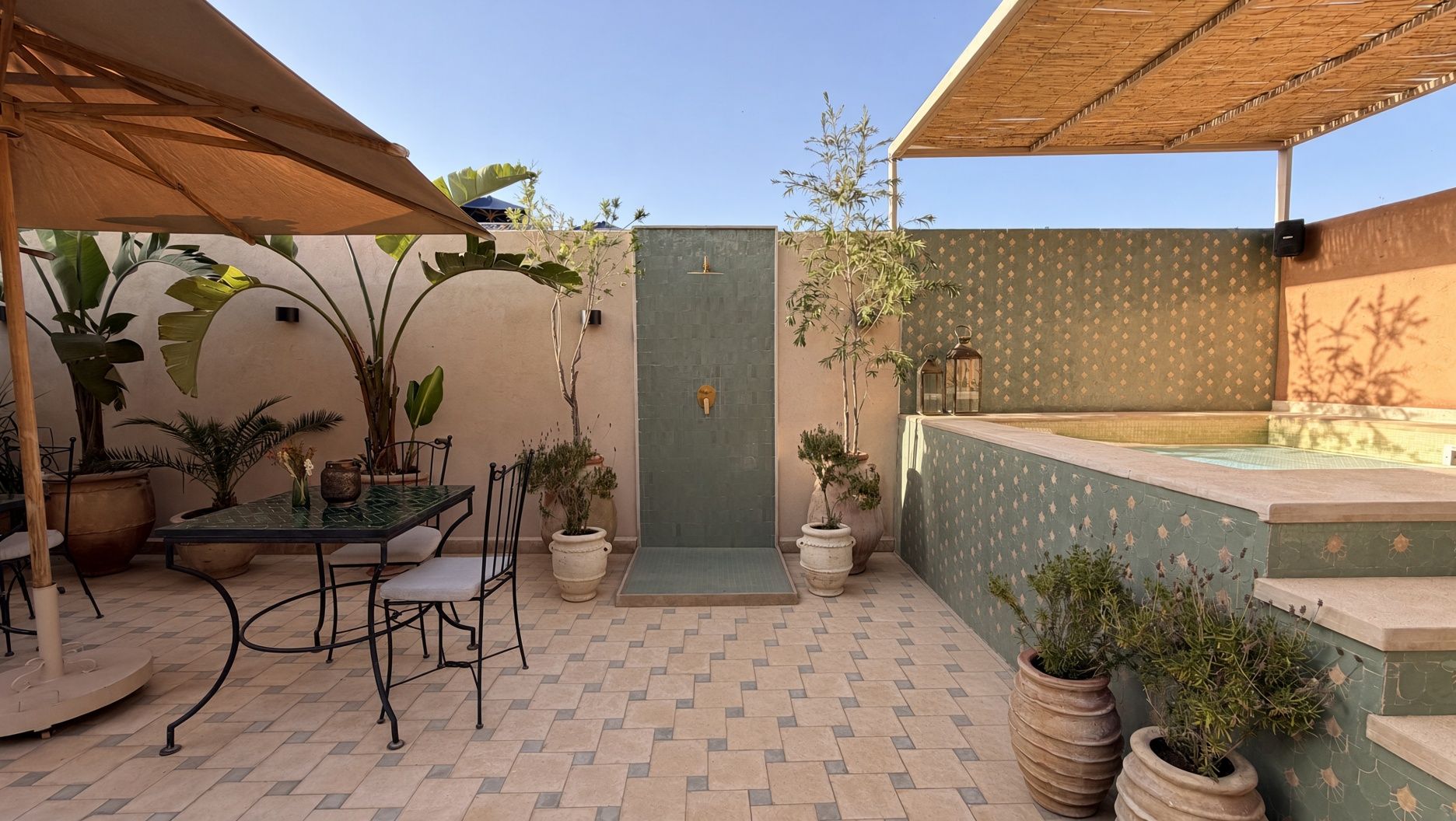 Un patio con mesa y sillas, plantas en macetas, una puerta y un jacuzzi pequeño.