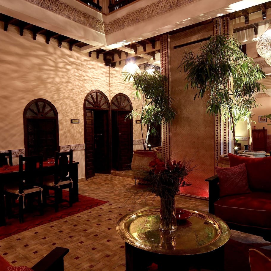 A lobby with a dining area, a reception desk, and a seating area with red upholstered chairs.