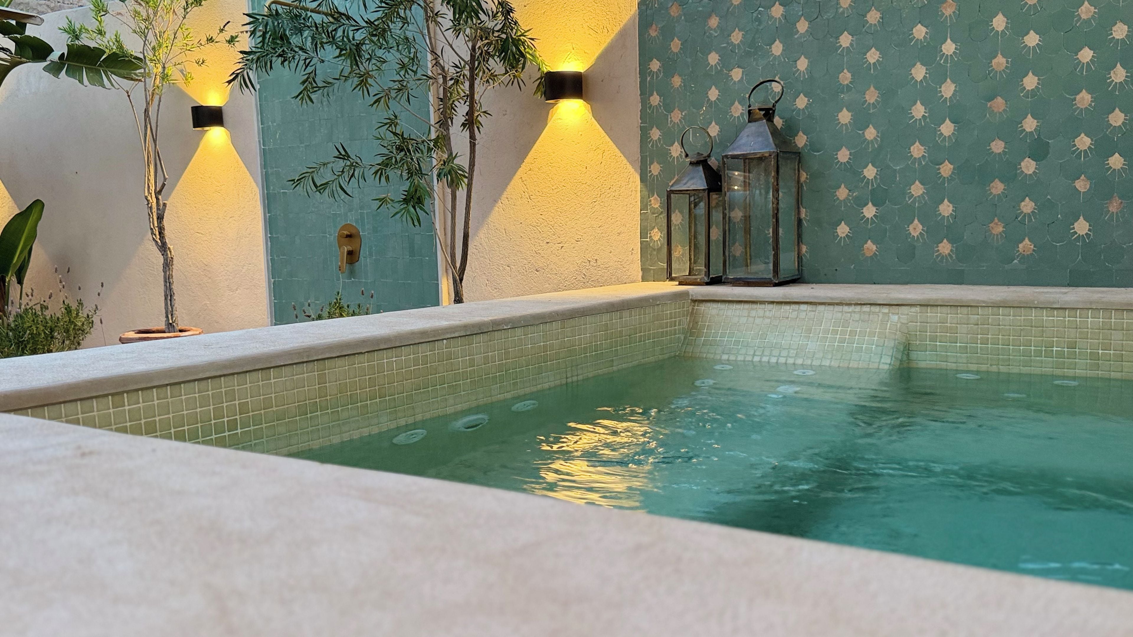 Ein Schwimmbecken mit gefliesten Wänden und einem kleinen Wasserfall.