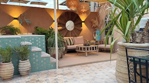 A cozy outdoor seating area with a sofa, coffee table, and potted plants. - Riad Jona (Marrakech)