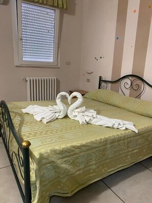Una cama con una colcha estampada, un radiador y una ventana con persianas.