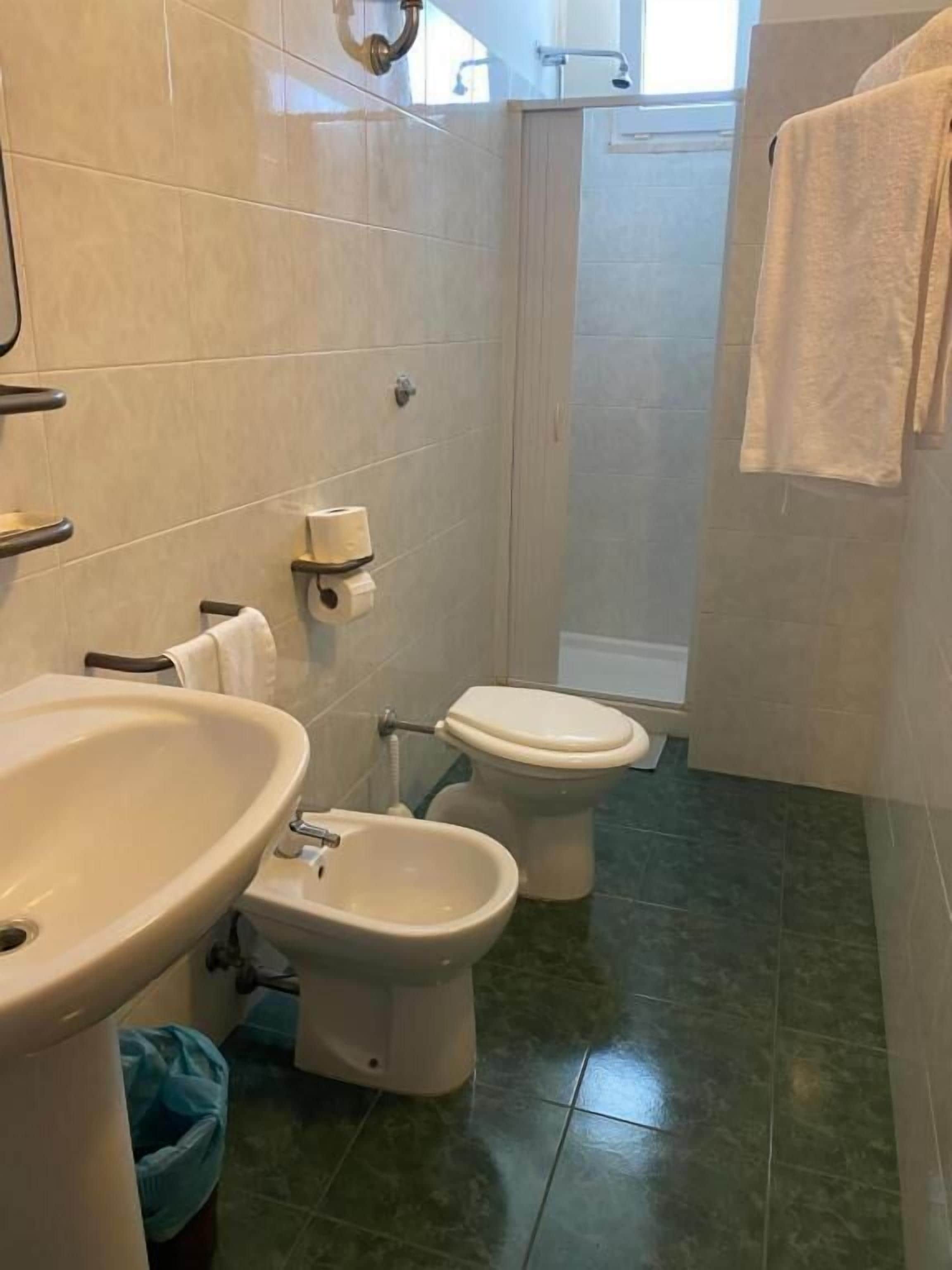 A bathroom with a sink, two toilets, and a bidet.