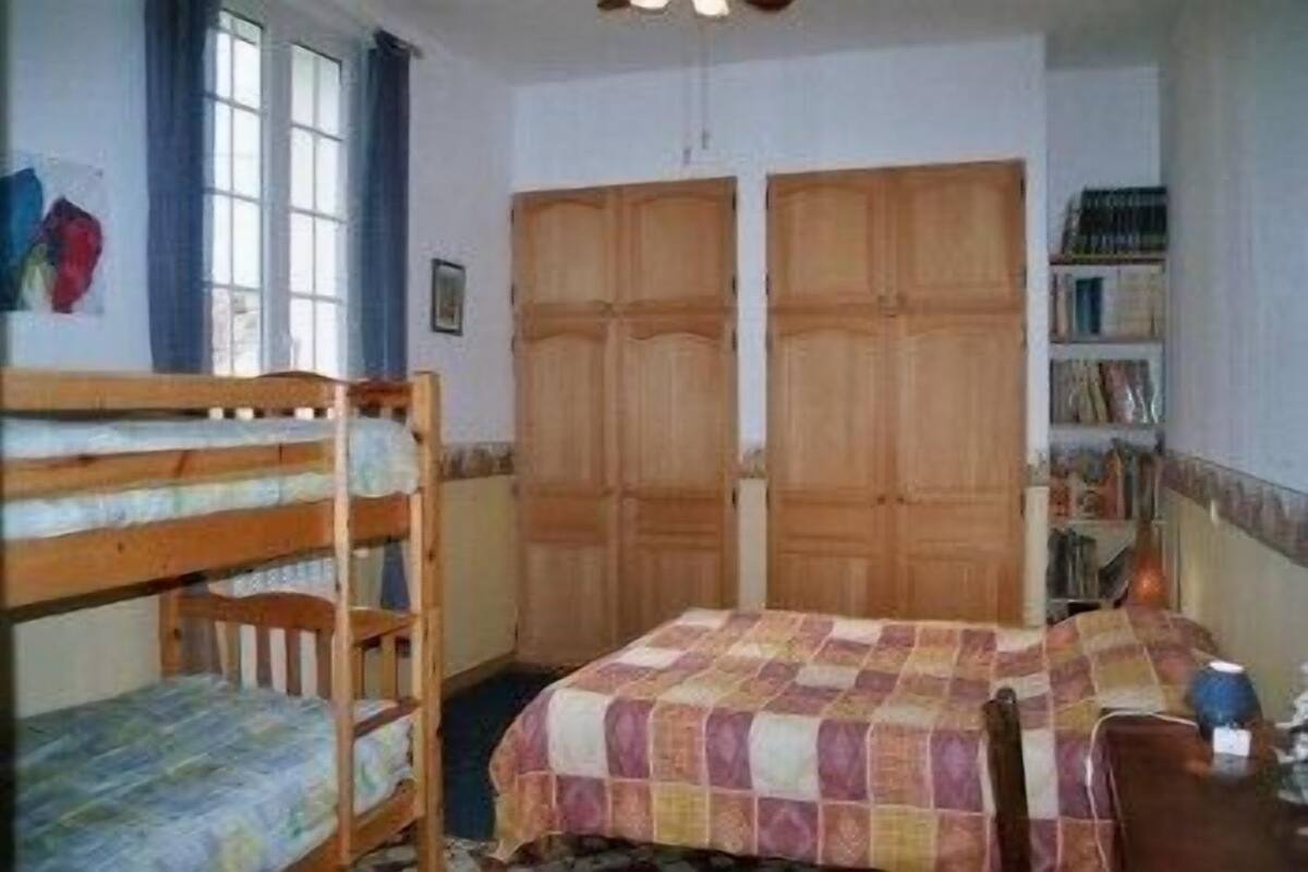 A bedroom with bunk beds, a wooden wardrobe, and a bookshelf.