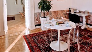 A dining area with a round table, chairs, a potted plant, and a patterned rug. - Palazzo De Giorgi (Lecce)
