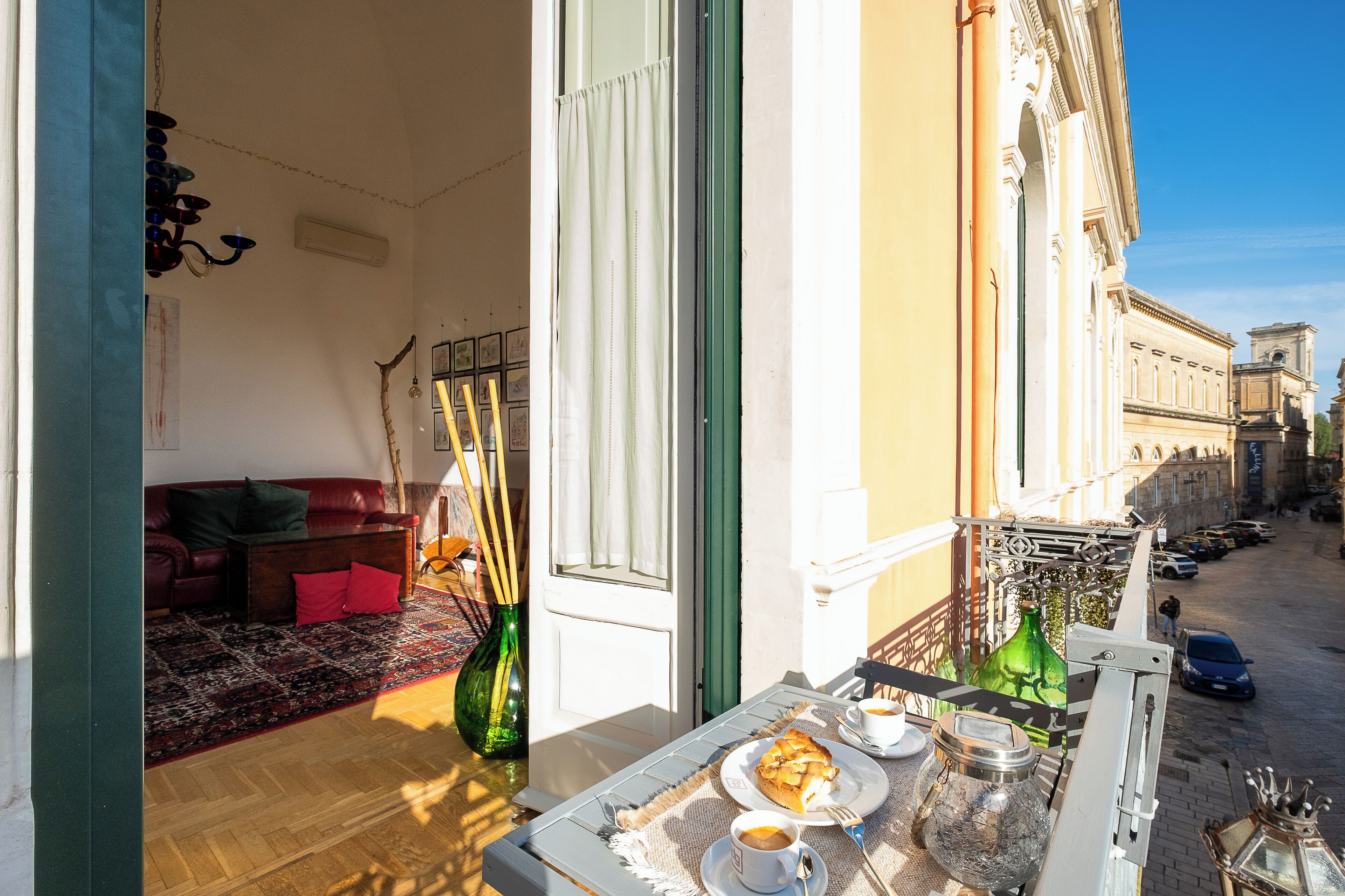 Un balcone con zona pranzo, inclusa una tavola, piatti, tazze e una bottiglia.