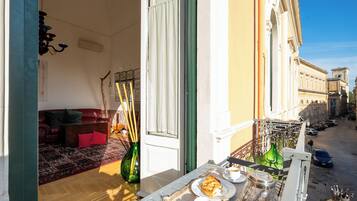 Un balcone con zona pranzo, inclusa una tavola, piatti, tazze e una bottiglia.