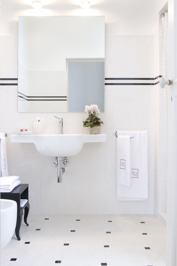 Une salle de bain moderne avec un lavabo blanc, un miroir et un sol carrelé.