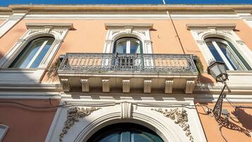 Facciata di un edificio con dettagli architettonici elaborati, tra cui un balcone con ringhiera in ferro battuto e un'ampia finestra ad arco.