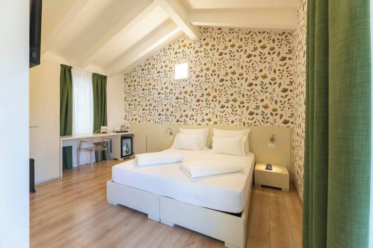 A bedroom with a large bed, a desk, and a chair.