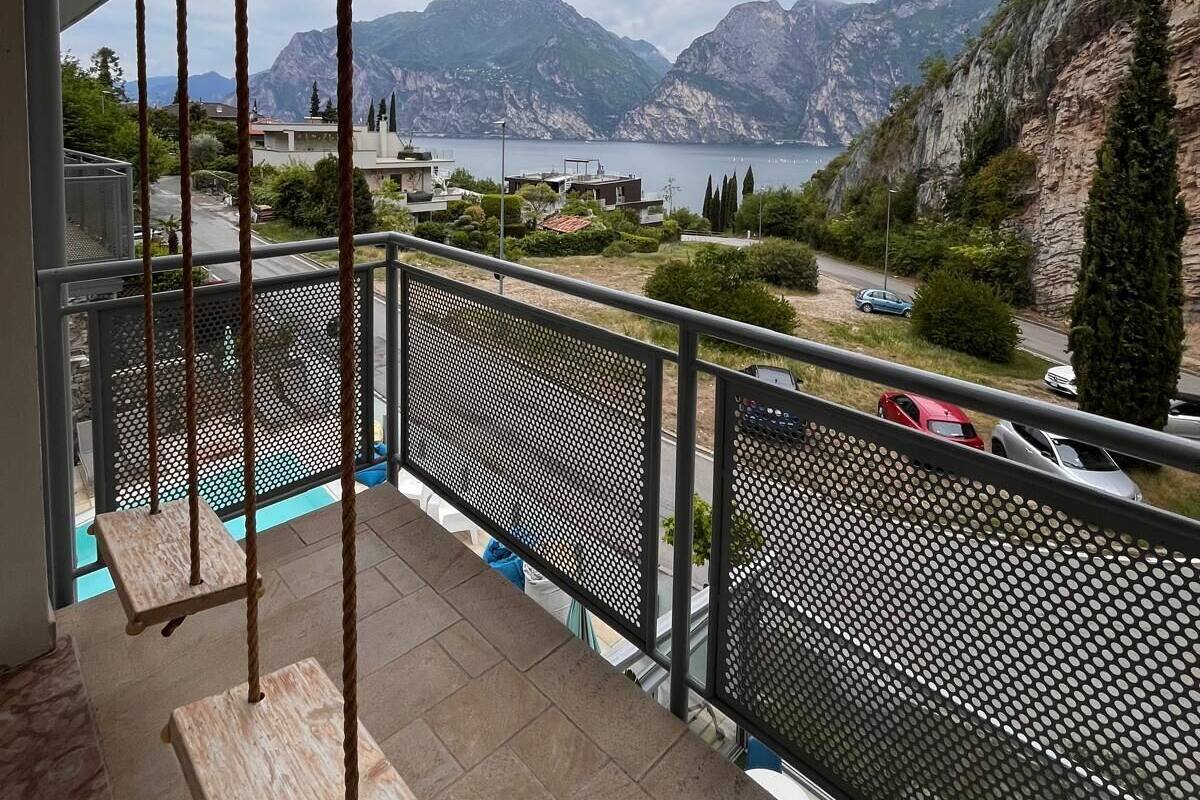 A balcony with a swing, a view of mountains, and a body of water.