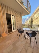 Un balcón con mesa y sillas, una hamaca y vistas a las montañas.