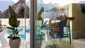 Une chambre moderne avec un mur de verre donnant sur une piscine et des montagnes.