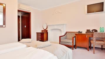 Una habitación de hotel con cama, escritorio, silla, televisor, armario y chimenea.