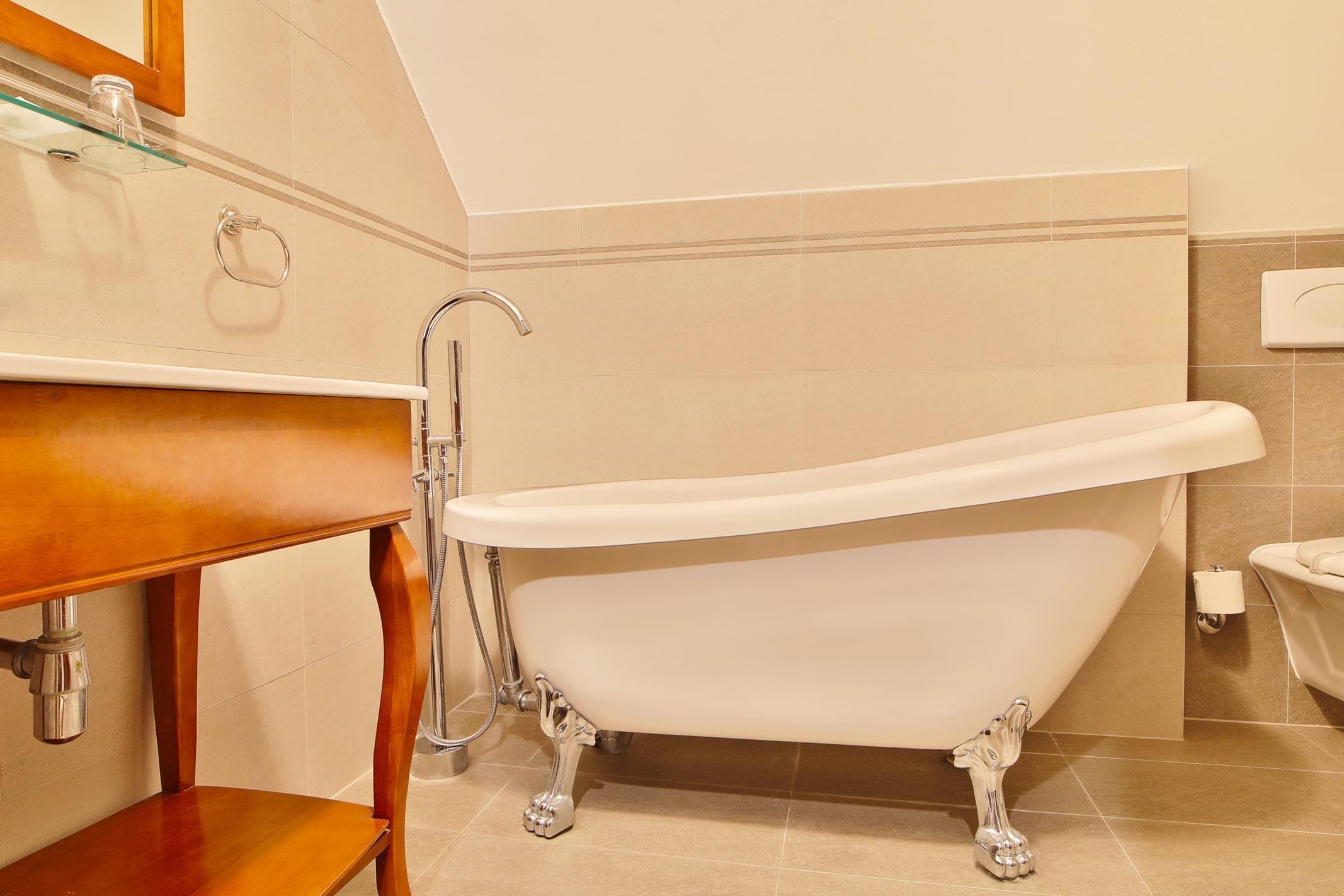A bathroom with a freestanding bathtub, a wooden vanity, and a glass shelf.