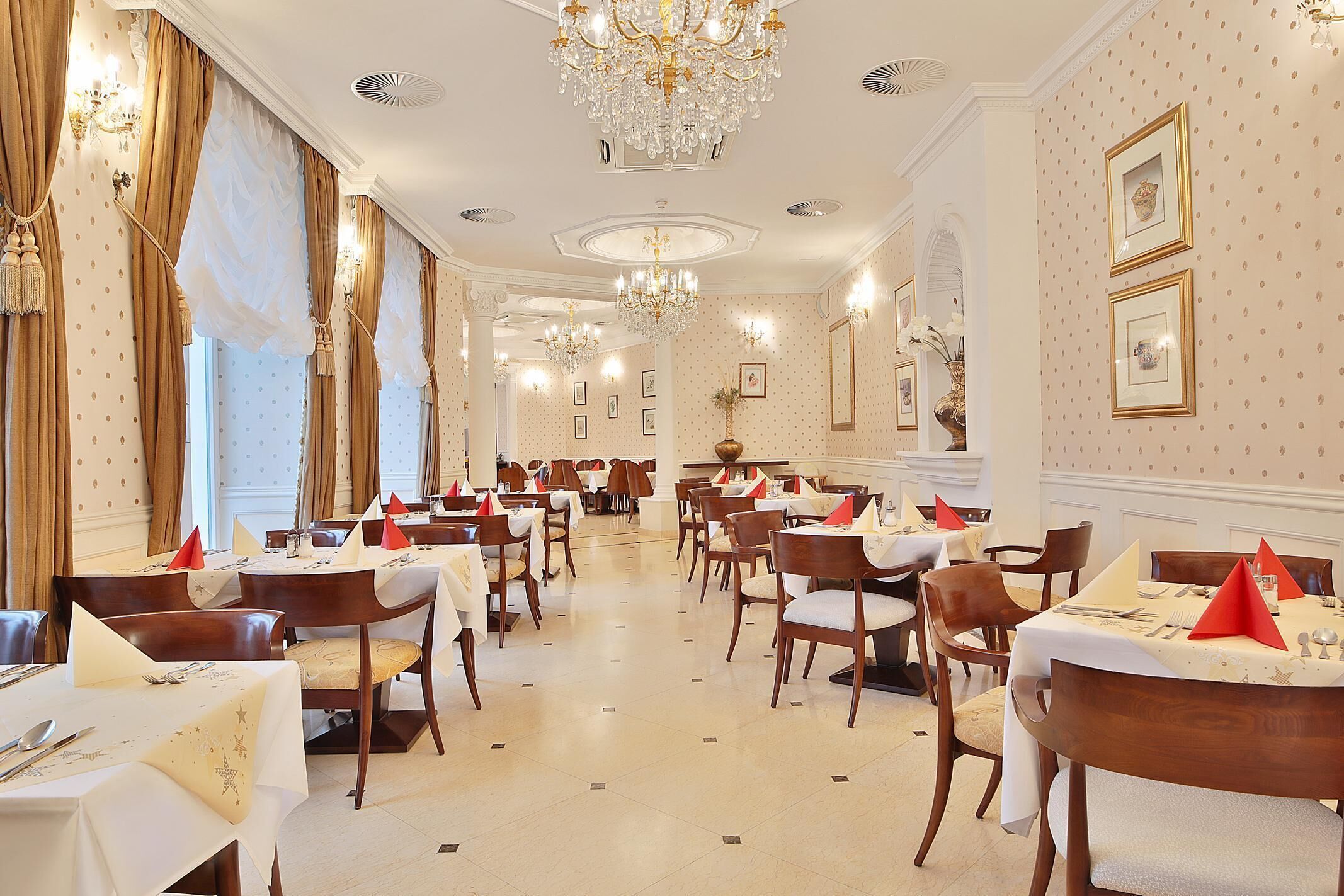Un comedor formal con varias mesas, sillas y candelabros.