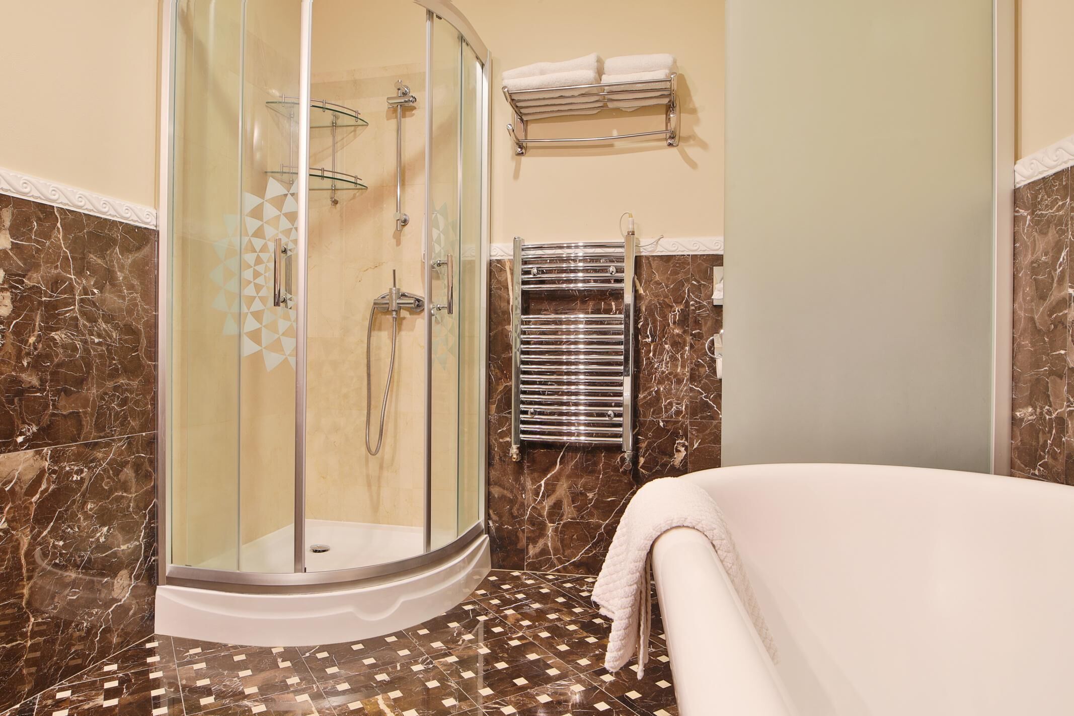 Un baño moderno con ducha acristalada, toallero empotrado y piso estampado.