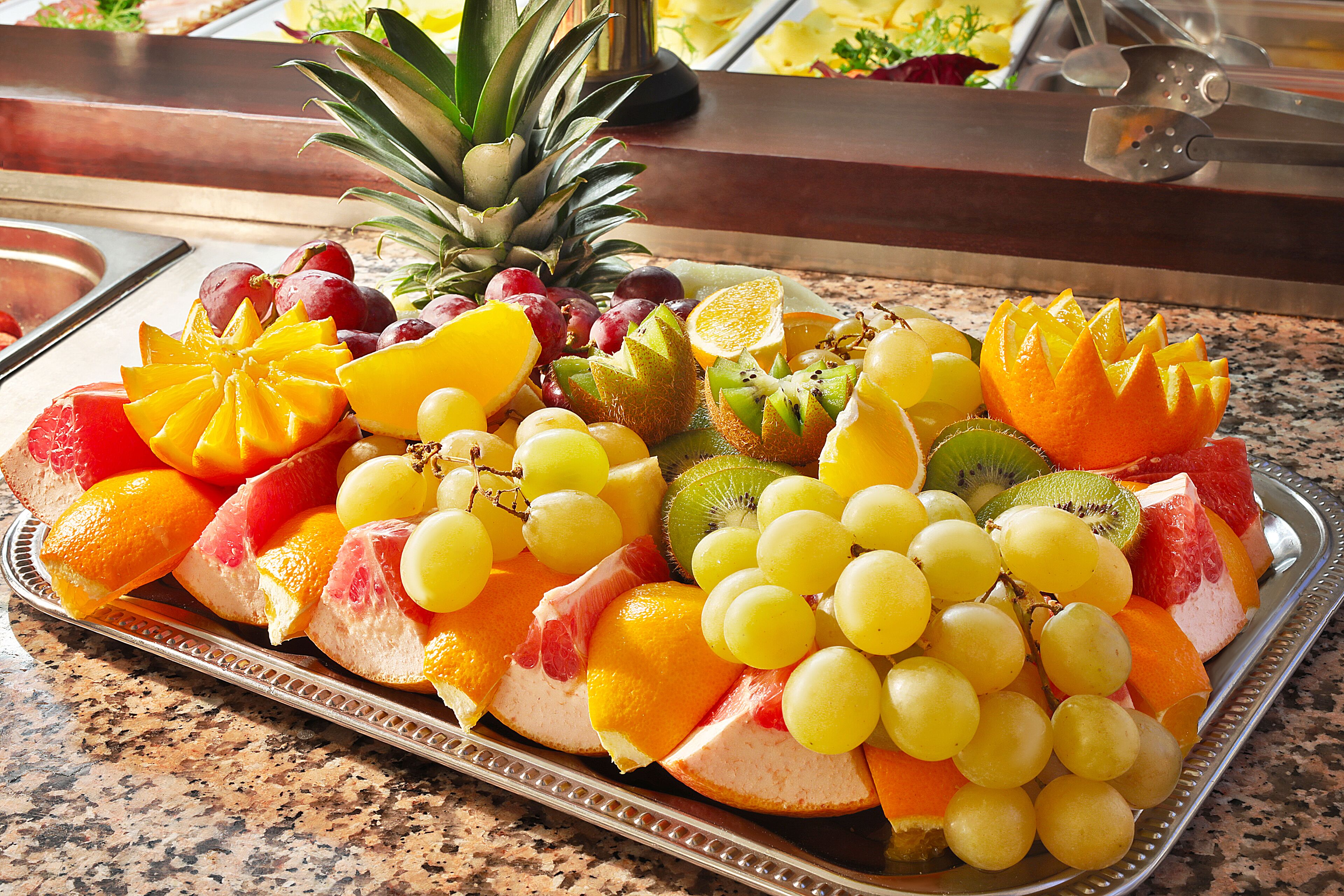 Una bandeja de frutas con diversas frutas como uvas, naranjas y kiwi.