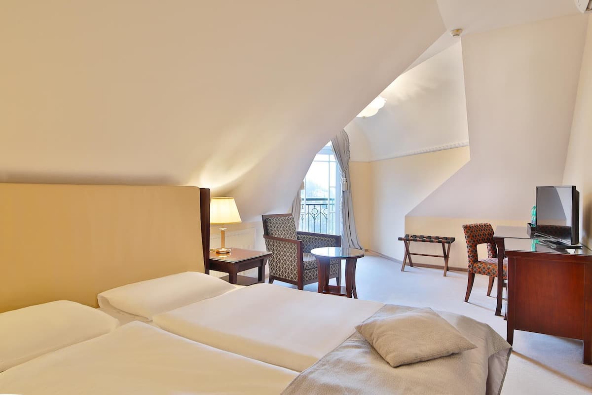 A hotel room with two beds, a desk, a chair, a television, and a balcony with a view.