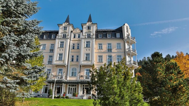 A large, multi-story building with a symmetrical facade, multiple balconies, and a central entrance with steps.