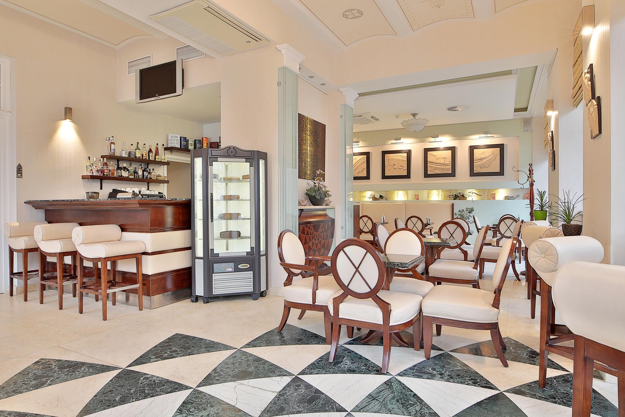Vestíbulo de hotel con zona de bar, asientos y suelo estampado.