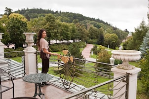 A balcony with ornate metal railings, a small table, and a decorative plant.
