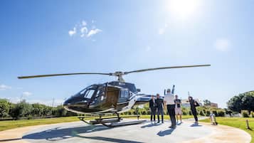 A helicopter parked on a concrete pad with a clear sky in the background.