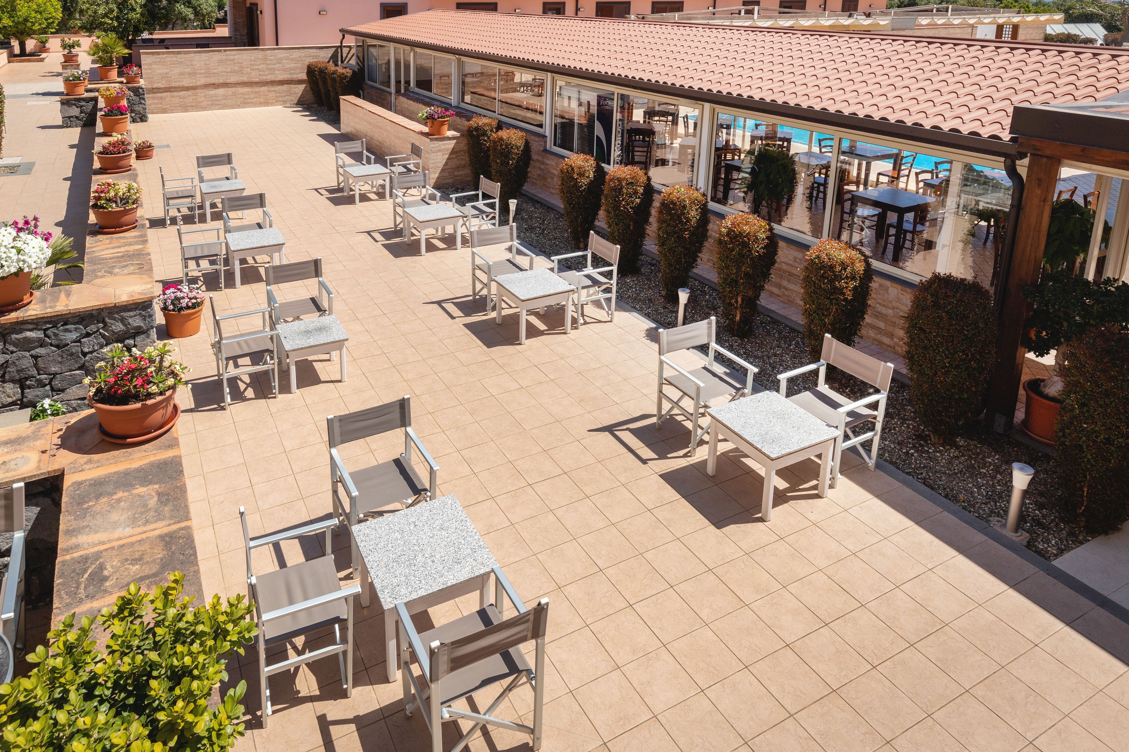 An outdoor patio area with multiple seating arrangements, including tables and chairs, and potted plants.