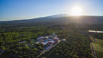 An aerial view of a property with a large building complex, surrounded by lush greenery and fields.