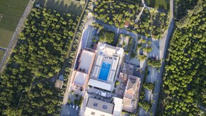 An aerial view of a residential area with a central building featuring a swimming pool, surrounded by trees and a small parking area. - La Terra dei Sogni Country Hotel (Fiumefreddo di Sicilia)