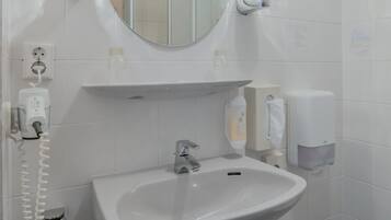 Une salle de bain avec un lavabo blanc, un miroir et un porte-serviettes.