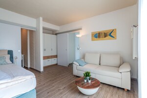 A modern, well-lit room with a bed, a sofa, and a coffee table.