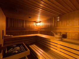 A wooden sauna with benches and a bucket.