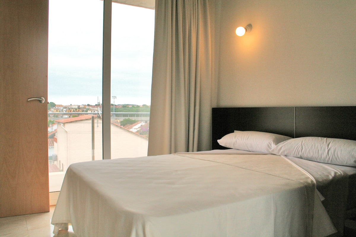 A hotel room with a large bed, a view through a sliding door, and a night light on the wall.