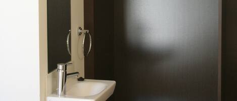 A bathroom with a white sink, a mirror, and wooden hangers on a rack.