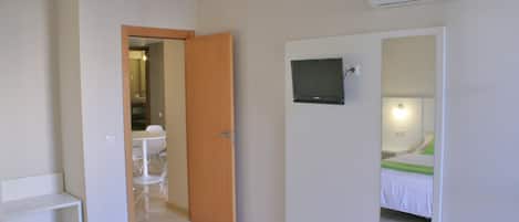 Une chambre d’hôtel équipée d’un lit, d’un téléviseur fixé au mur, d’un miroir et d’un appareil de climatisation.