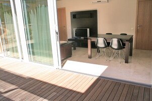 Un comedor moderno con una mesa y sillas, televisión y puerta corrediza de vidrio que da a un espacio al aire libre.