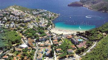 Vista aérea de uma cidade costeira com praia, edifícios residenciais e um amplo estacionamento.