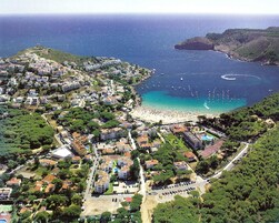 An aerial view of a coastal town with a beach, residential buildings, and a large parking area.