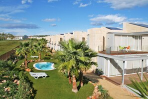 A modern resort with a swimming pool, palm trees, and a rooftop deck. - L'Escala Resort (L'Escala)