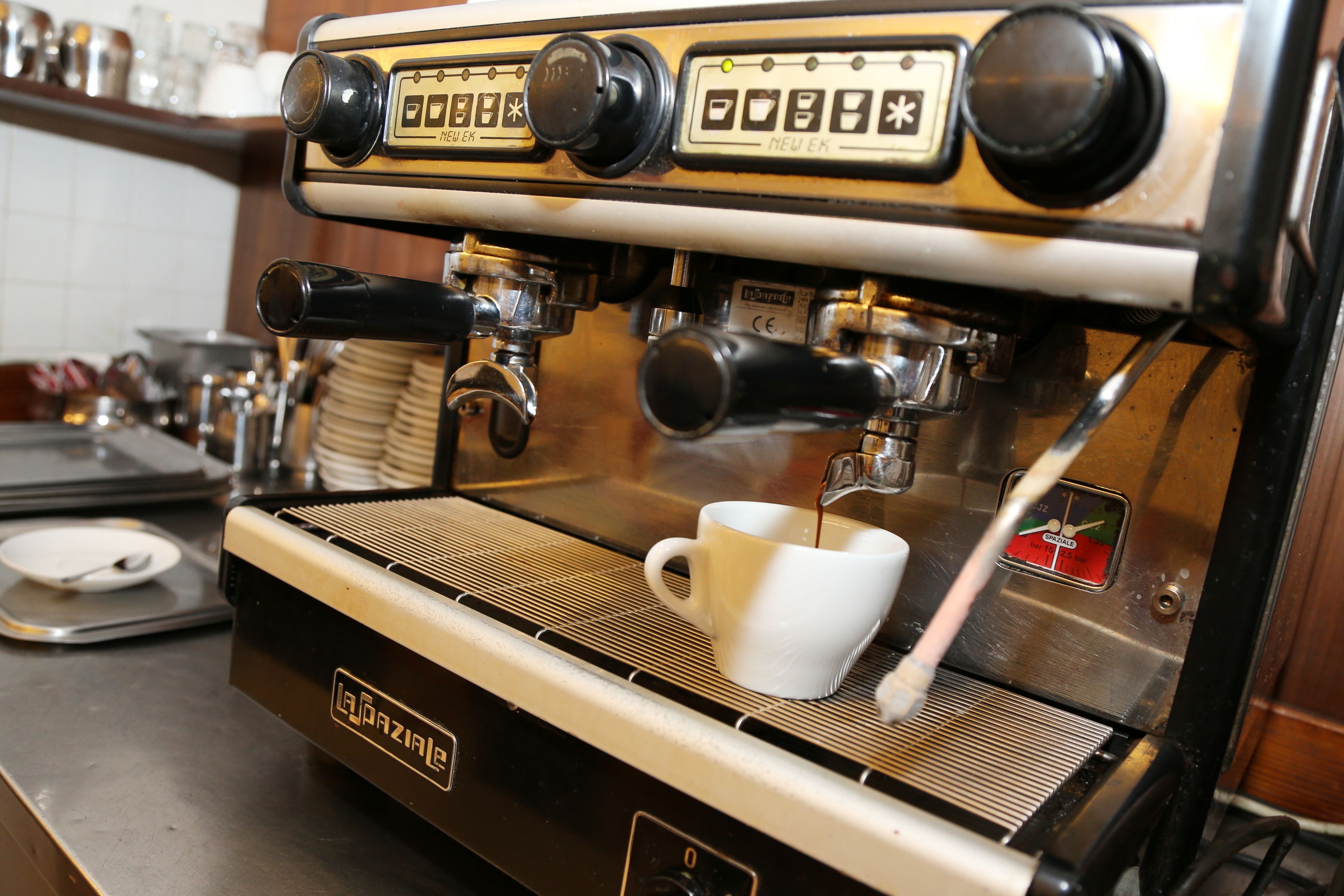 A La Bazar coffee machine with a white cup of coffee being brewed.